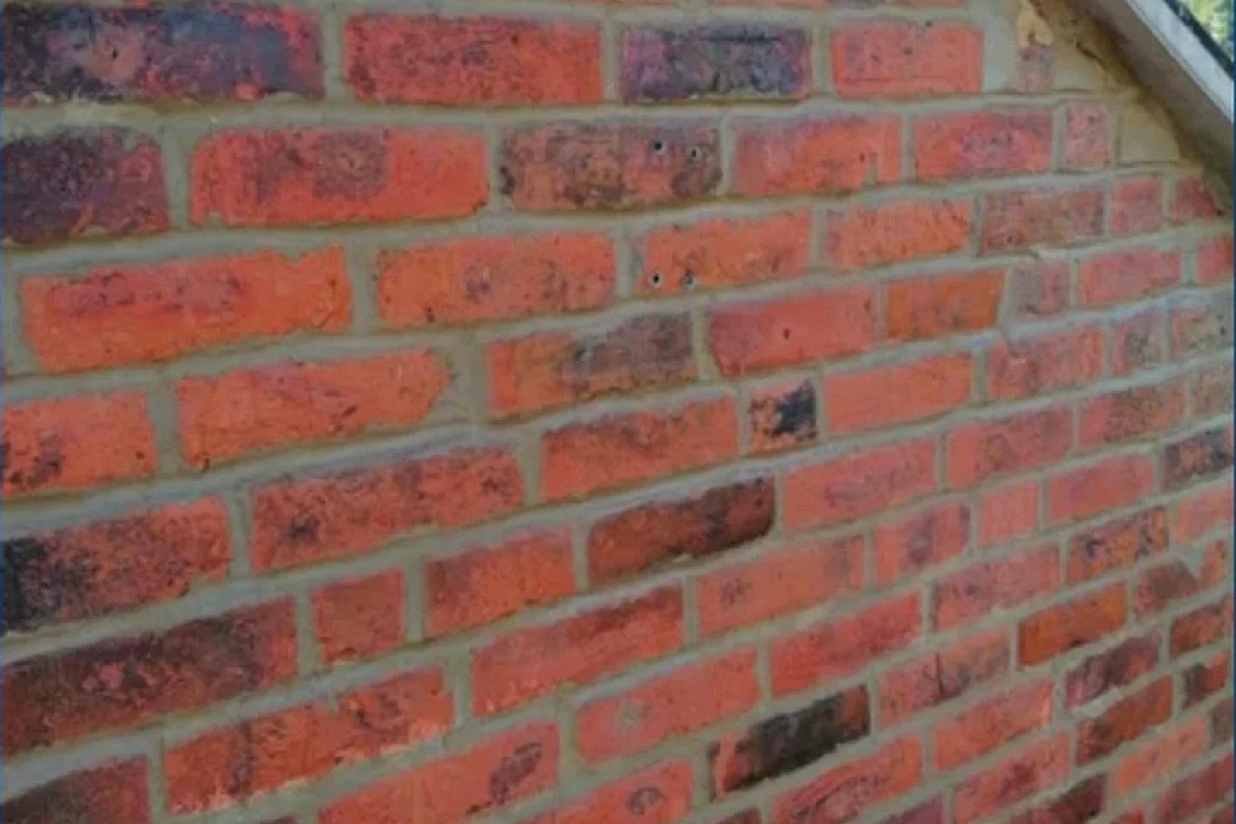 Renewed mortar joints across a red brick gable wall